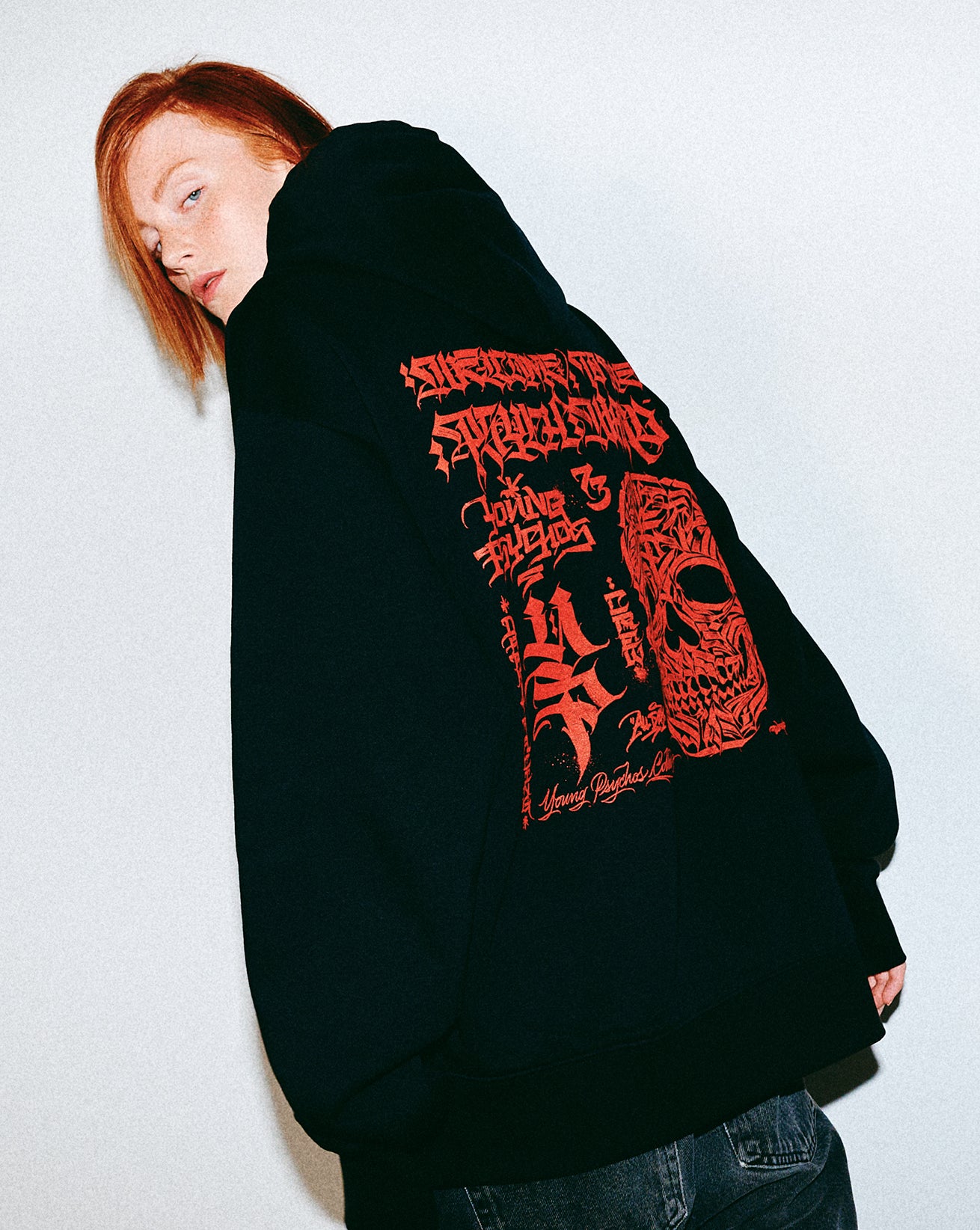 Person wearing a black hoodie with red text and graphics on the back against a white background