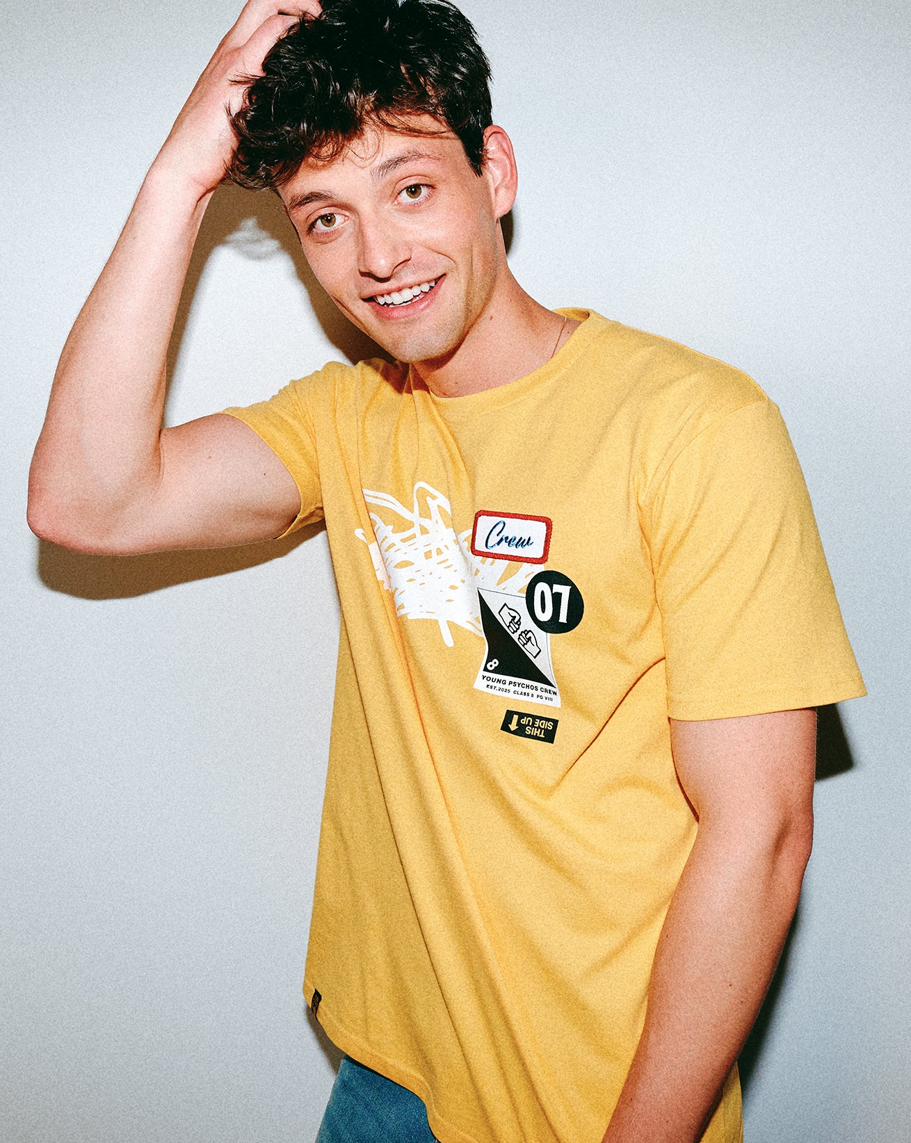 Person wearing a yellow t-shirt with graphic designs on a plain background