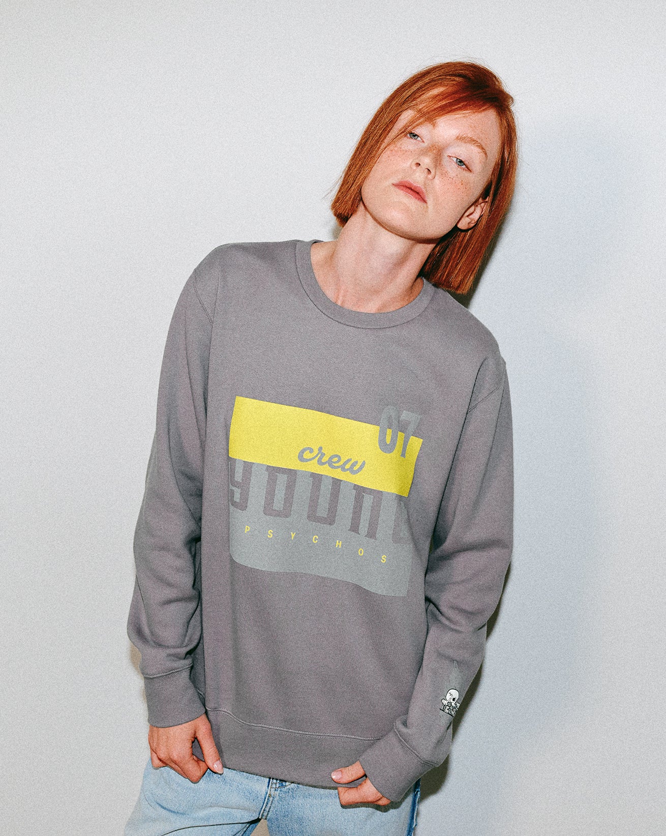 Person wearing a gray sweatshirt with a yellow accent on a plain background