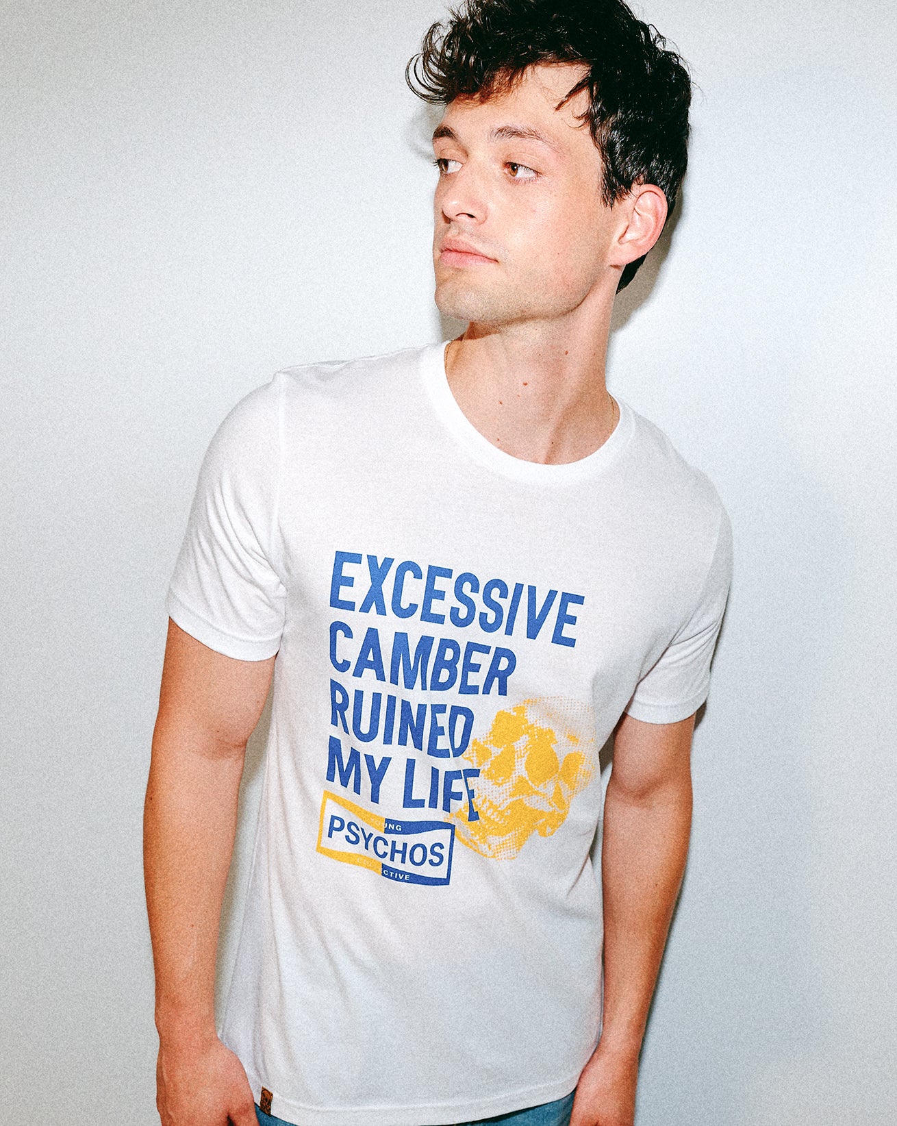 Person wearing a white t-shirt with blue and yellow text and graphics.