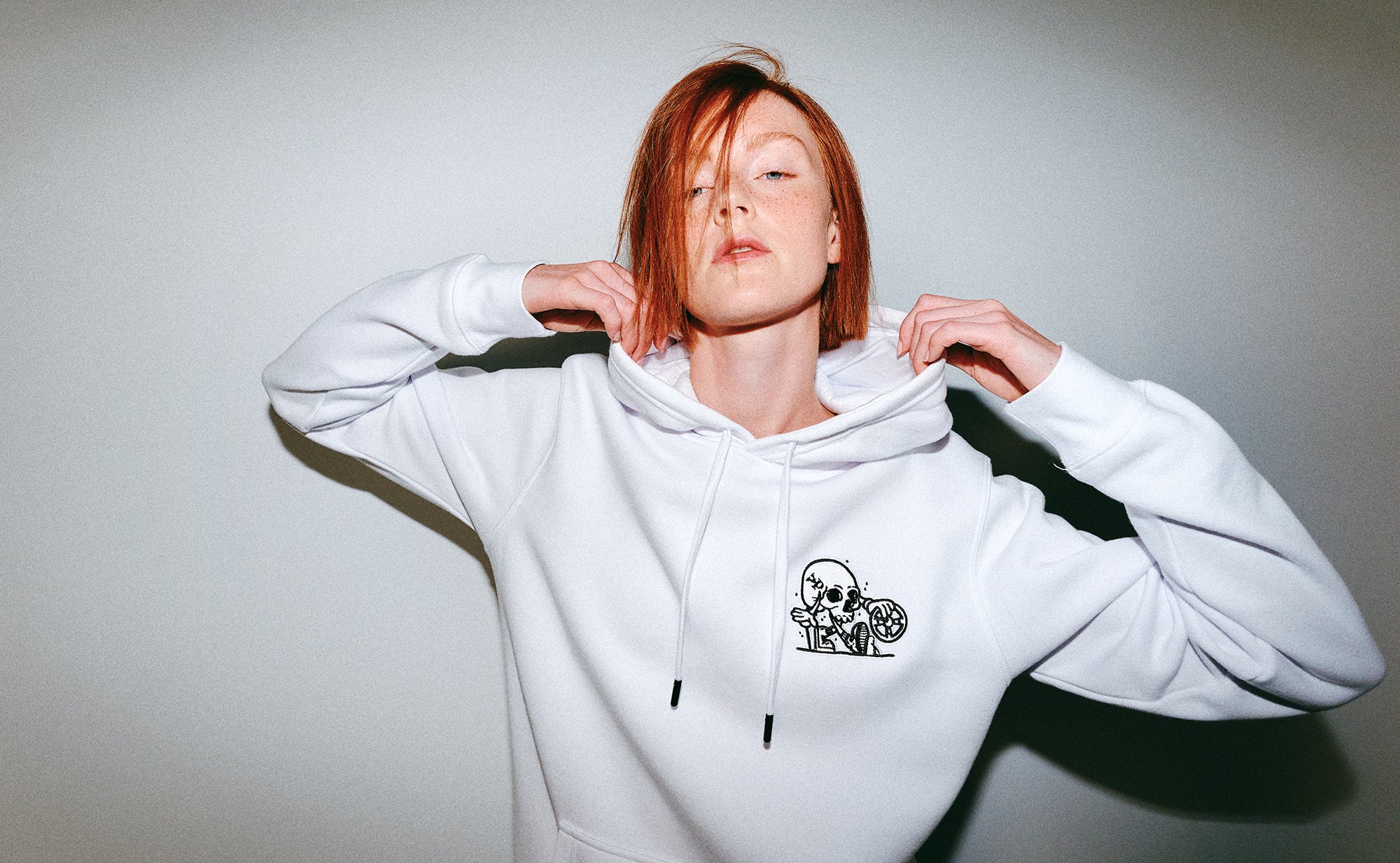 Person wearing a white hoodie with a small Young Psychos logo on a plain background
