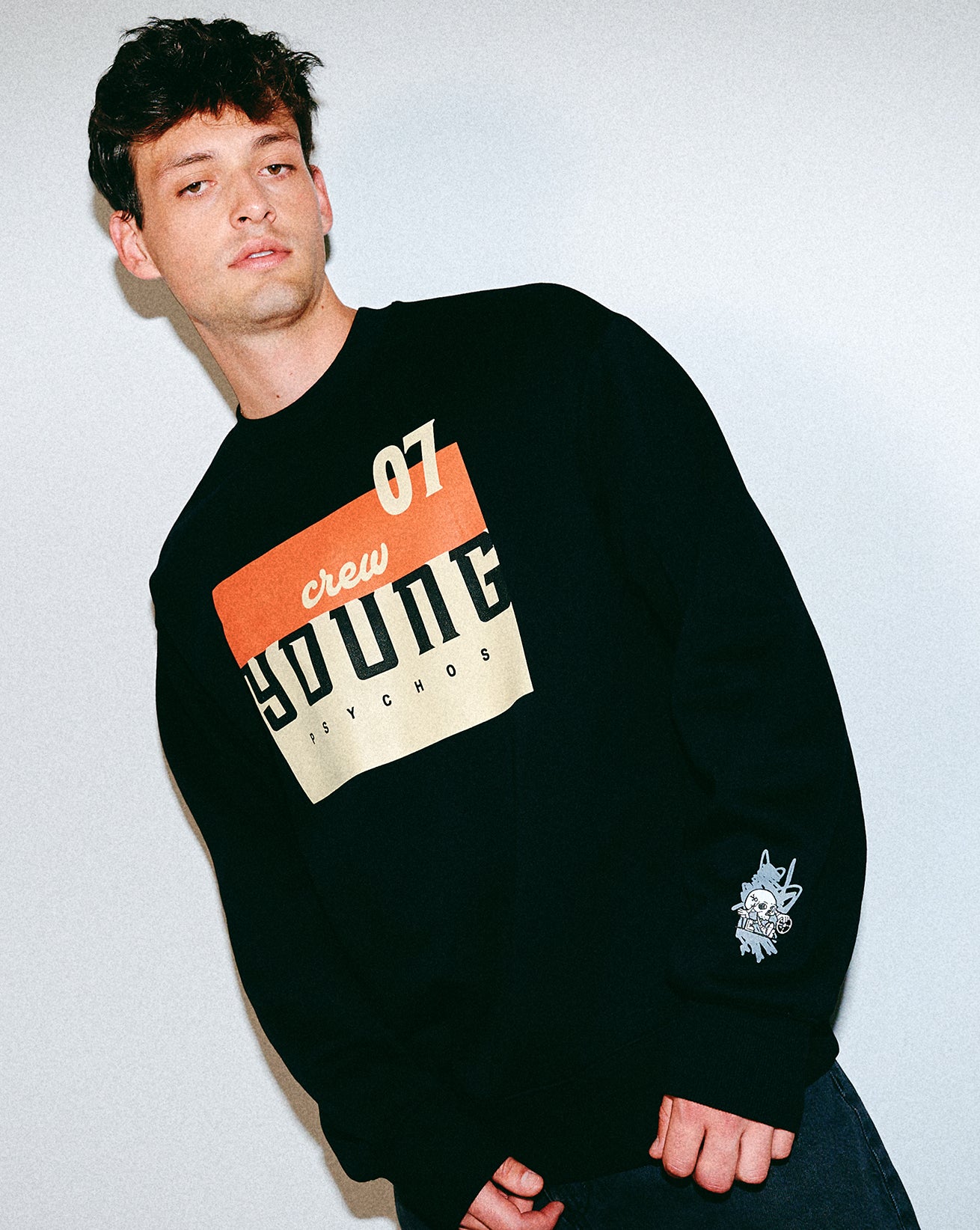 Man wearing a black sweatshirt with orange and white text on a light gray background