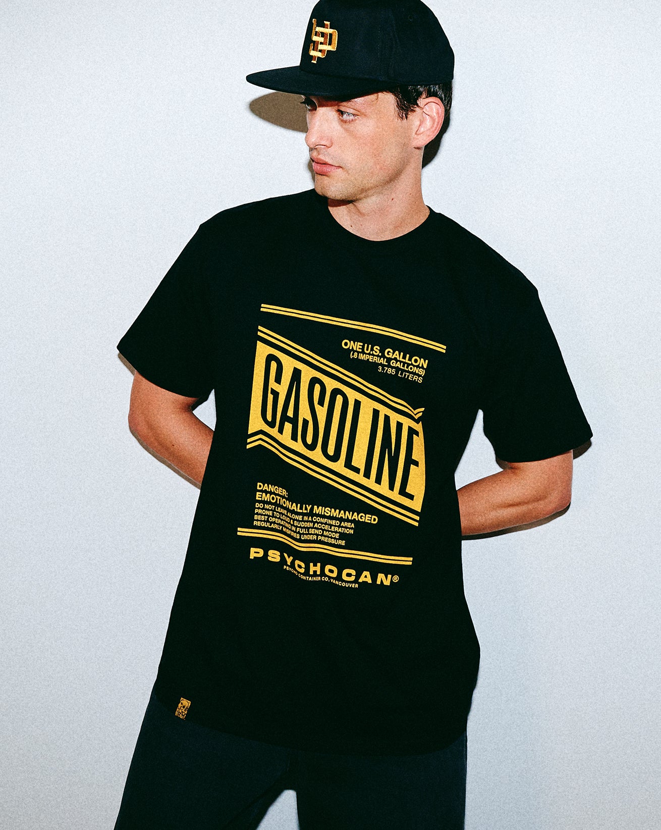 Man wearing a black t-shirt with yellow text and graphics on a plain background